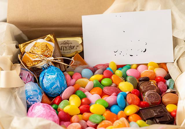 Open sweet hamper showing wrapped chocolates, colourful sweets and a handwritten gift card
